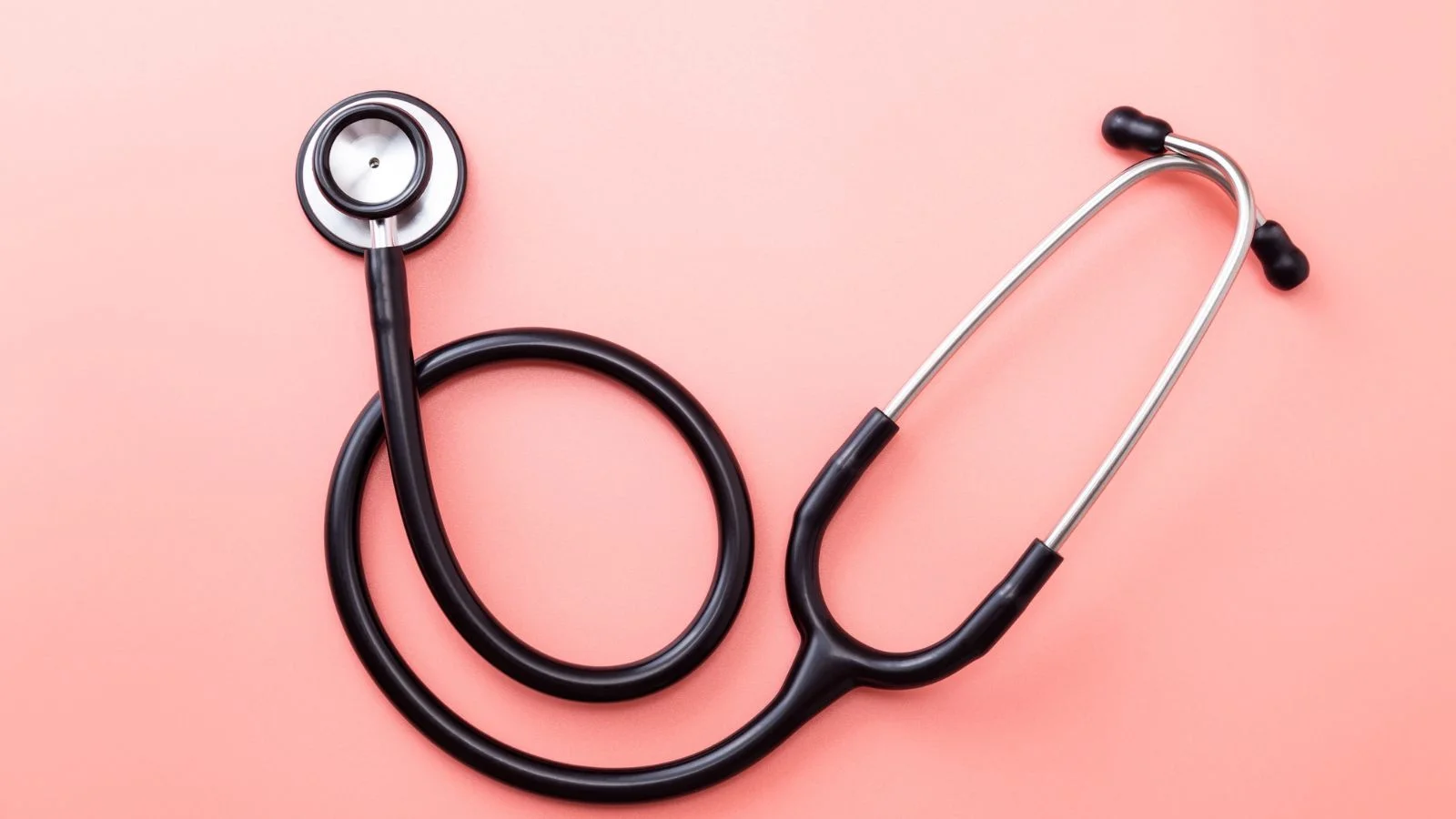 A physician's stethoscope on a warm pink background