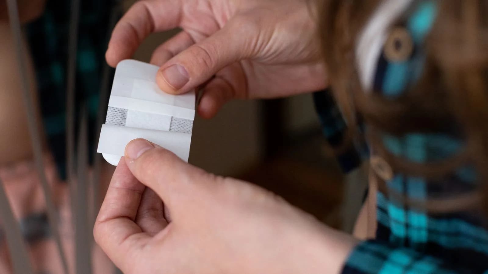 Close-up of hands peeling the paper backing from a transdermal hormone replacement therapy patch