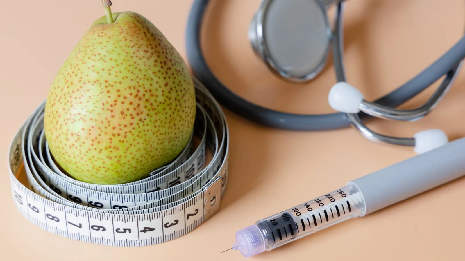A semaglutide injection pen beside a measuring tape, pear, and stethoscope, representing physician-supervised weight loss
