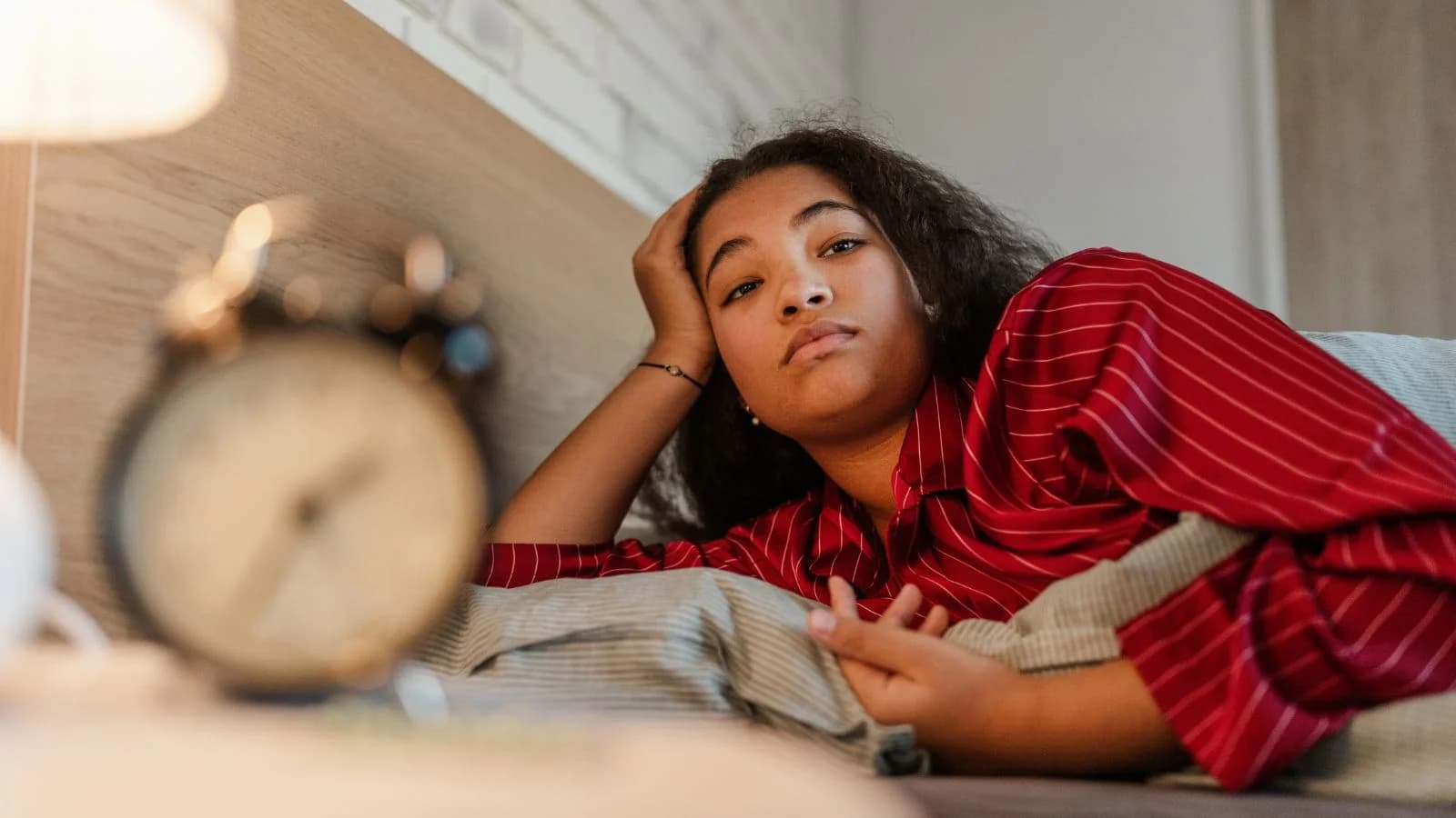 A tired woman lying awake in bed, the kind of fatigue and poor sleep that can signal a hormone imbalance