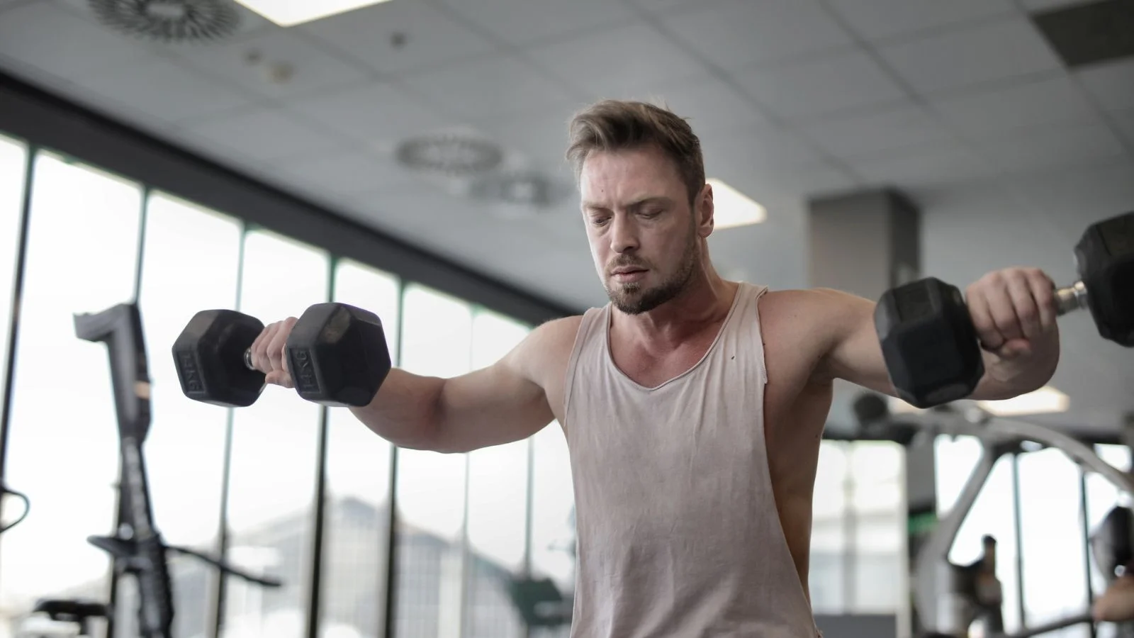 A man lifting dumbbells at the gym, working on the strength and energy that testosterone therapy supports