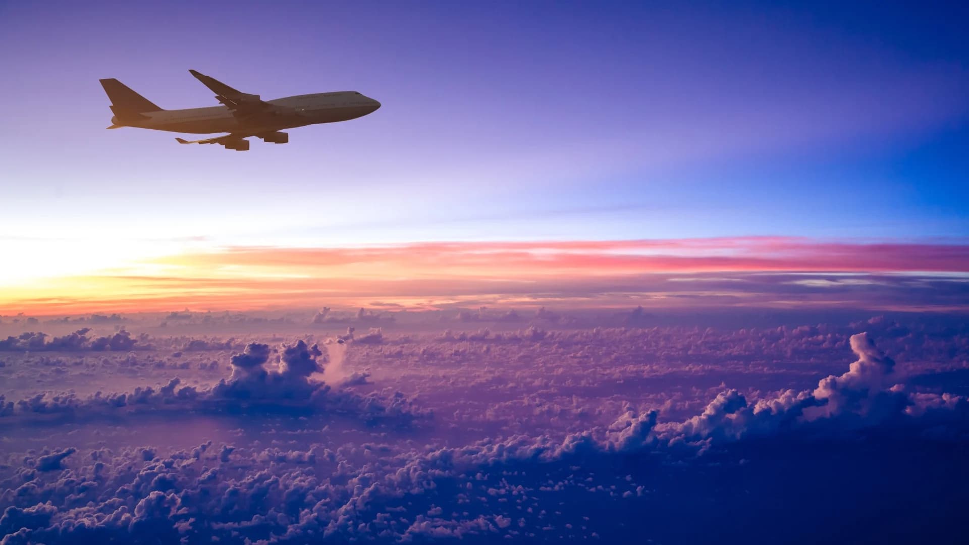 An airplane above the clouds at sunset
